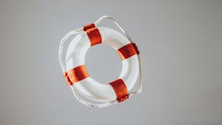 White and red life ring on light grey background to illustrate drowning dream