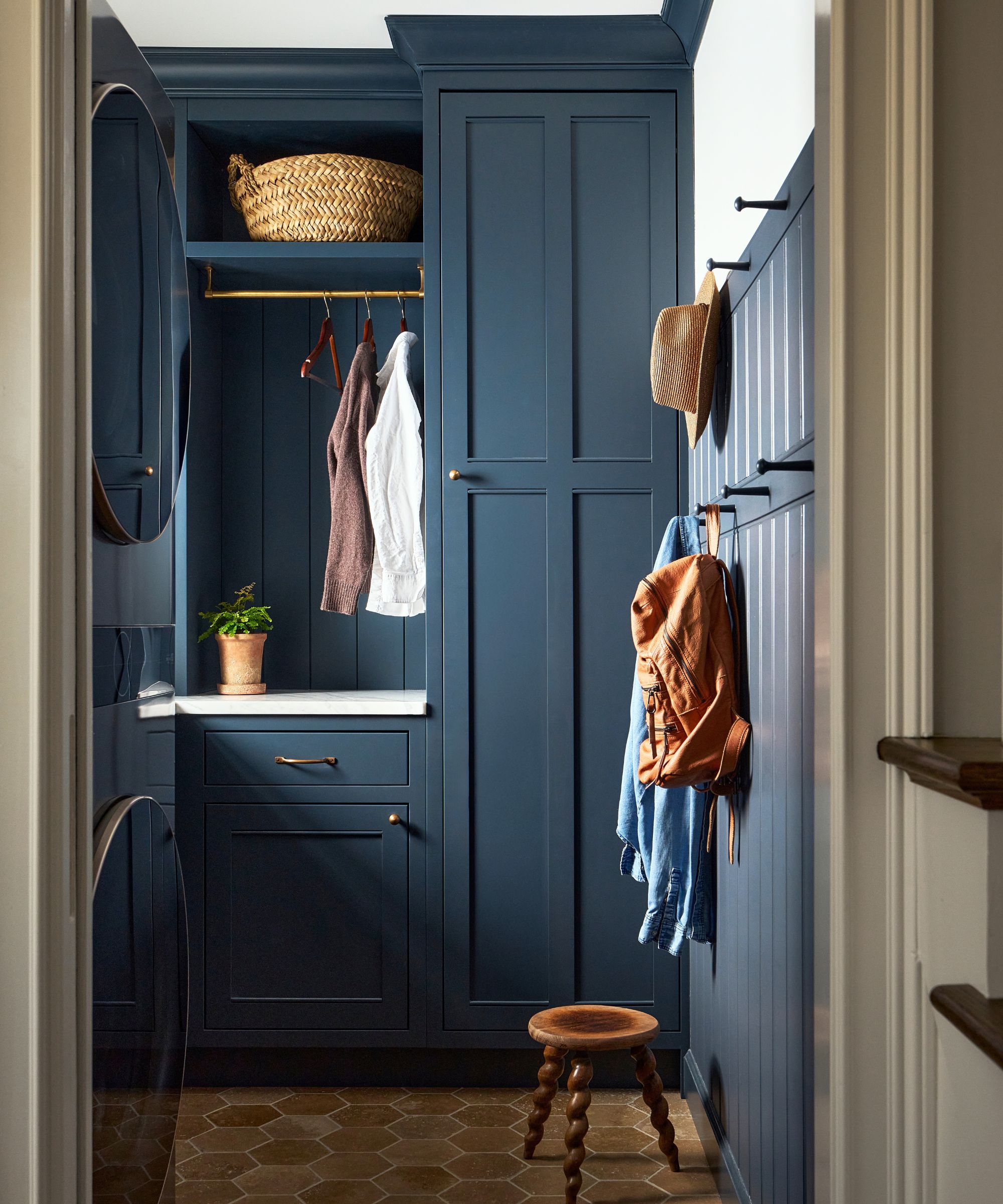 Small laundry attic room with navy blue cabinetry and wall paneling with hooks