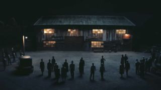 A group of shadowed figures surround a building at night in Sinners