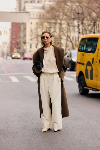 woman wearig brown coat, cream pants, and cream top