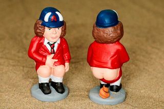 An Angus Young "Caganer" figurine, dropping its pants to pass a perfectly coiled stool
