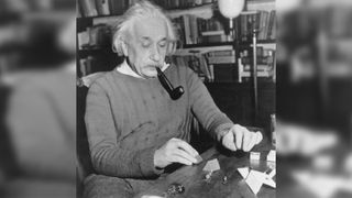 Albert Einstein smoking a pipe at his desk