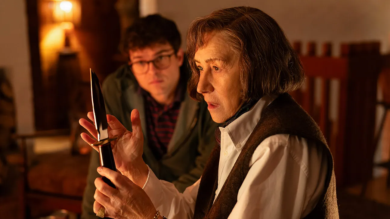 An older woman (Helen Mirren as Patricia Highsmith) holds up a knife in admiration as a young man (Alden Ehrenreich as Edward Ridgeway) leans in to look, in a still from 'A Talent for Murder.'