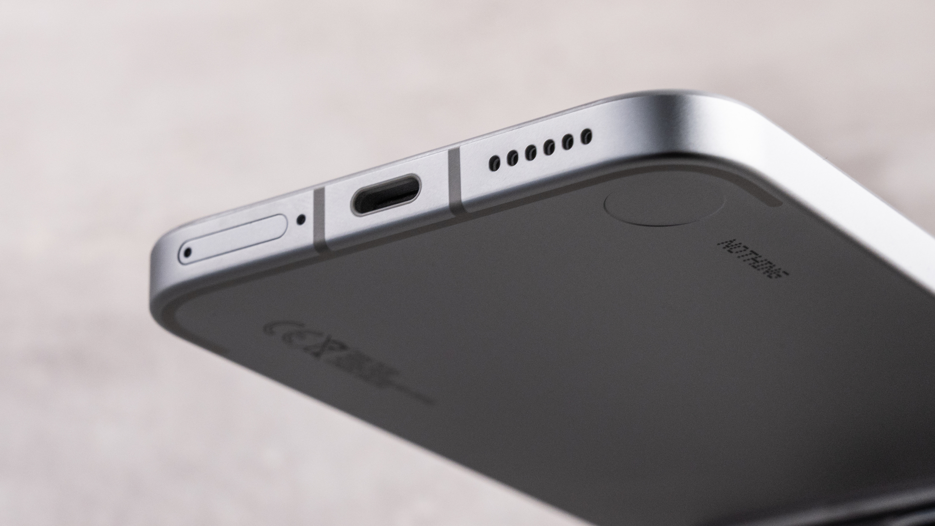 A closeup of the Nothing Phone (4a) Pro's ports, showing its SIM slot, USB-C charging port and speaker.