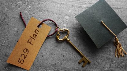A gold key with a 529 plan tag sitting next to a mini graduation cap.