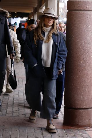 Jennifer Lopez is seen on December 29, 2024 in Aspen, Colorado wearing a cowboy hat, navy blue barn jacket, oat-colored turtleneck sweater, barrel jeans, and lug-sole tan boots.