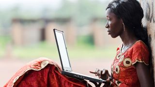 Street Shot of an African Ethnicity young woman working on business holding her technology item computer in a university in Bamako, Mali. 