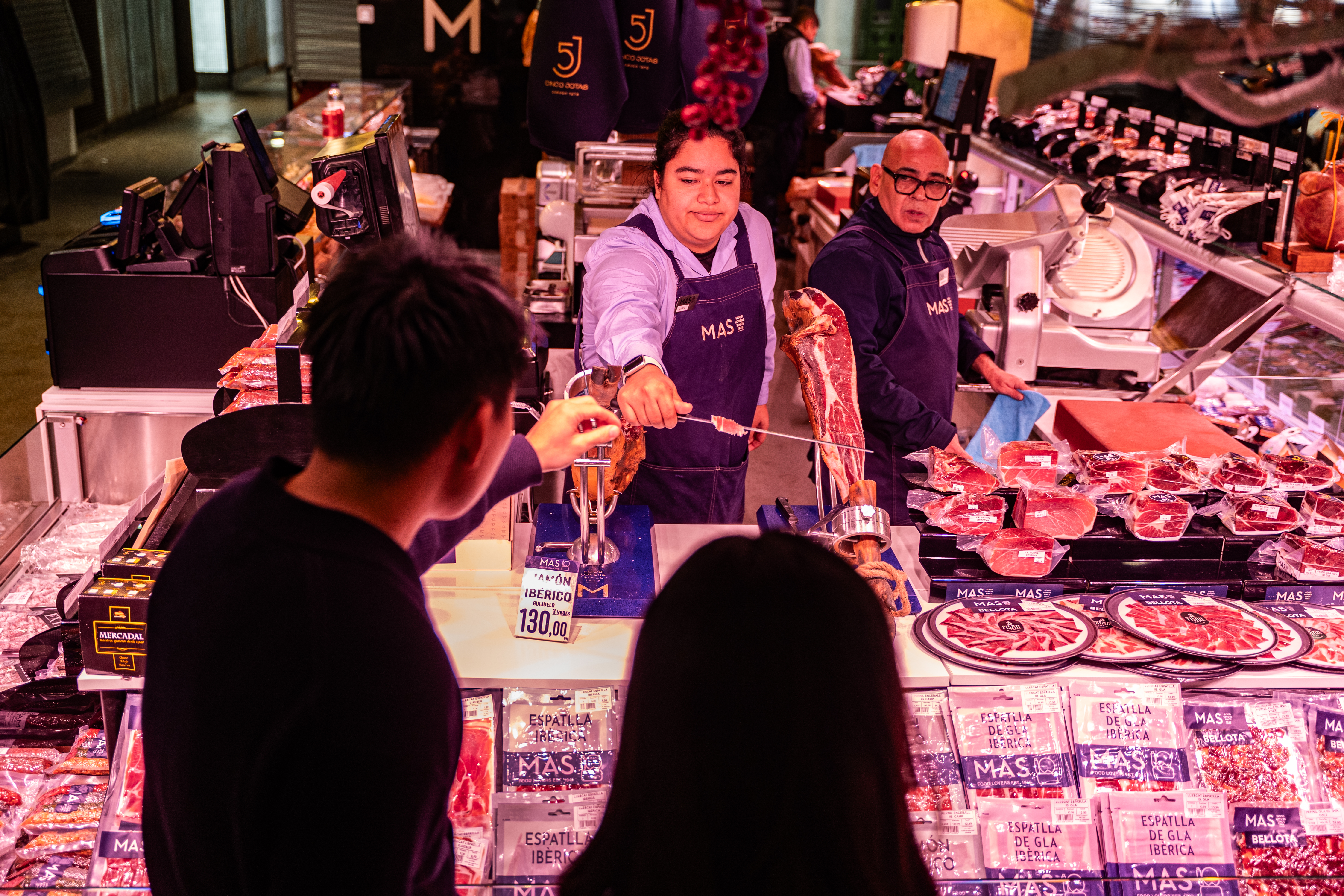 An employee hands jamon to visitors at La Boqueria