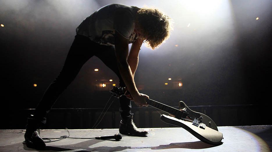 Generic view of a guitarist in a rock band in silhouette smashing a guitar on the stage while performing, taken in May 2009 in London, the group is called Caimbo