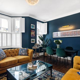 Blue living room with white window, yellow sofa and patterned cushions