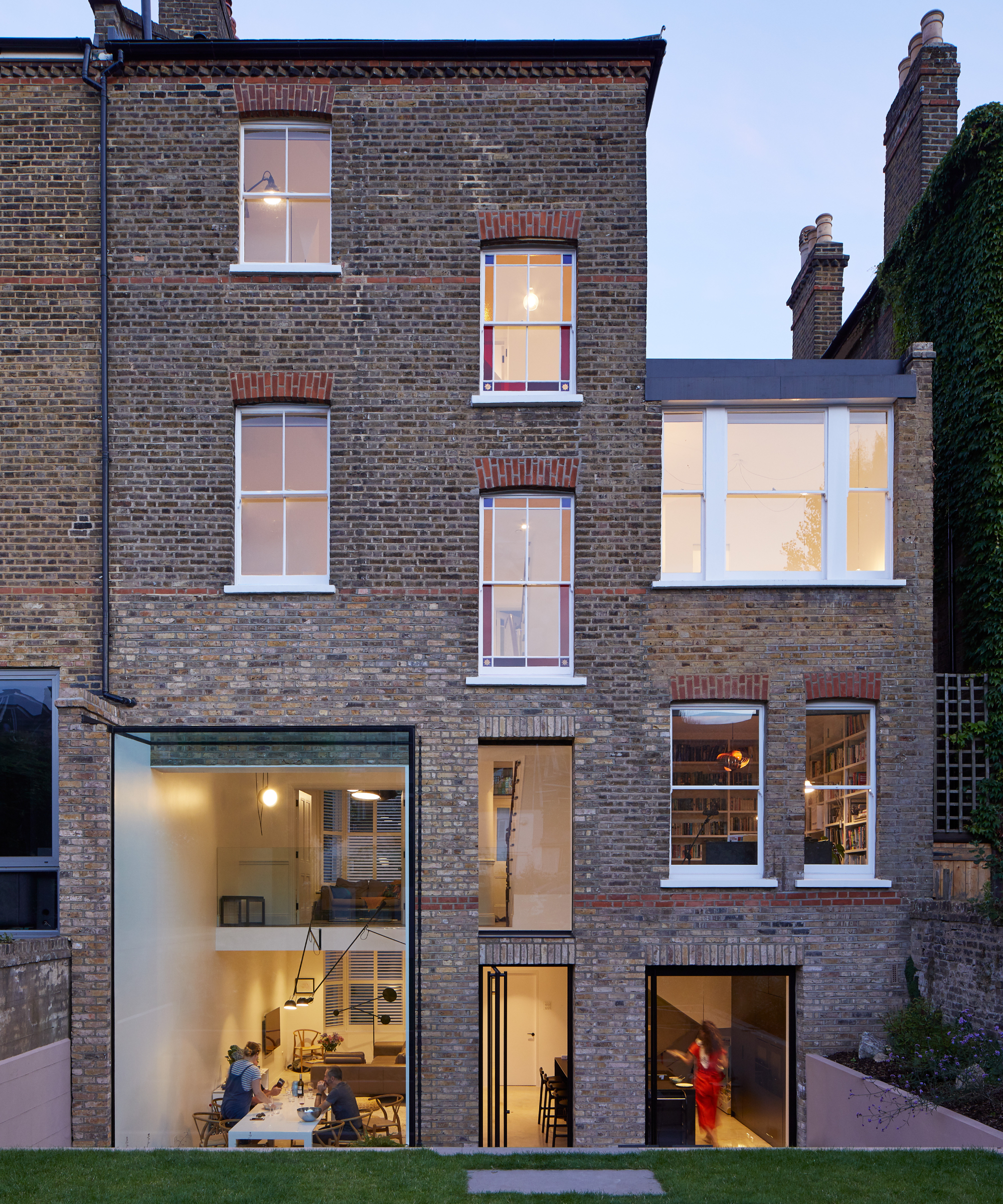 exterior of terraced house with large glazed section to lower ground and ground floor showing double height space inside