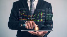 Businessman using tablet with virtual trading charts and financial analytics dashboard, showing stock market data