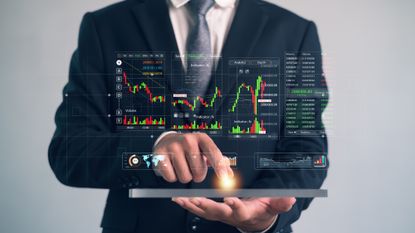 Businessman using tablet with virtual trading charts and financial analytics dashboard, showing stock market data