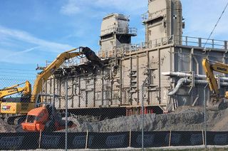 An excavator tears into the side of Mobile Launch Platform-2 (MLP-2), one of three Apollo and space shuttle support structures. MLP-2 is being demolished to make way for a new Space Launch System (SLS) mobile launcher.