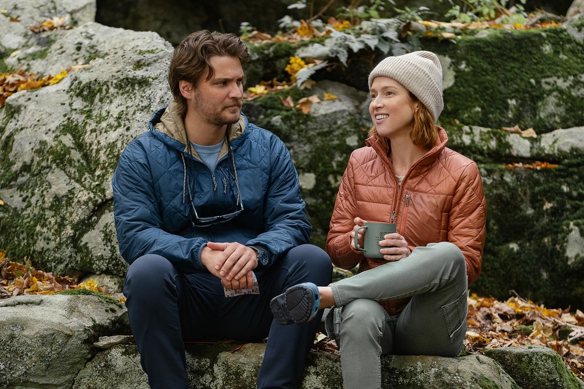 Jake and Helen sitting on some rocks. Helen is smiling and holding a cup.