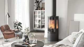 black log burner with flue in living room with white walls, wooden floor and seating