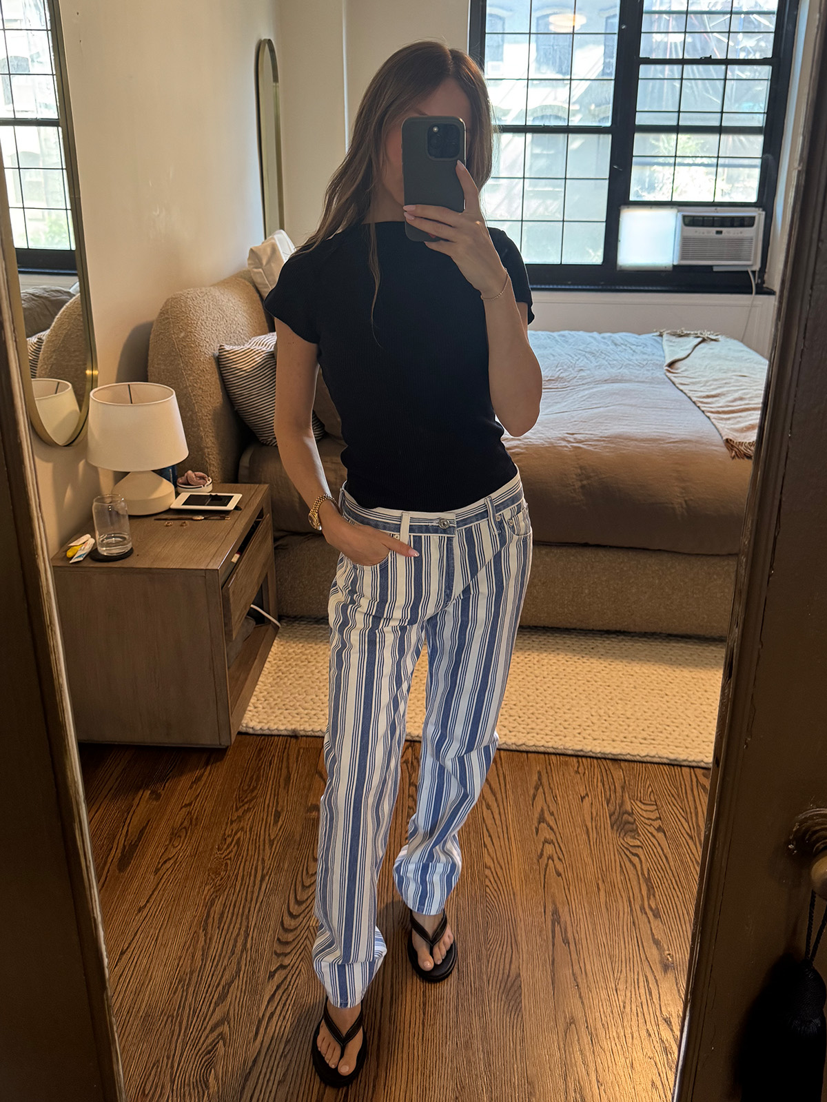 Nikki wears a navy tee and blue stripe jeans with flip-flops.