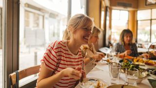 Woman eating spicy food at a restaurant with friends