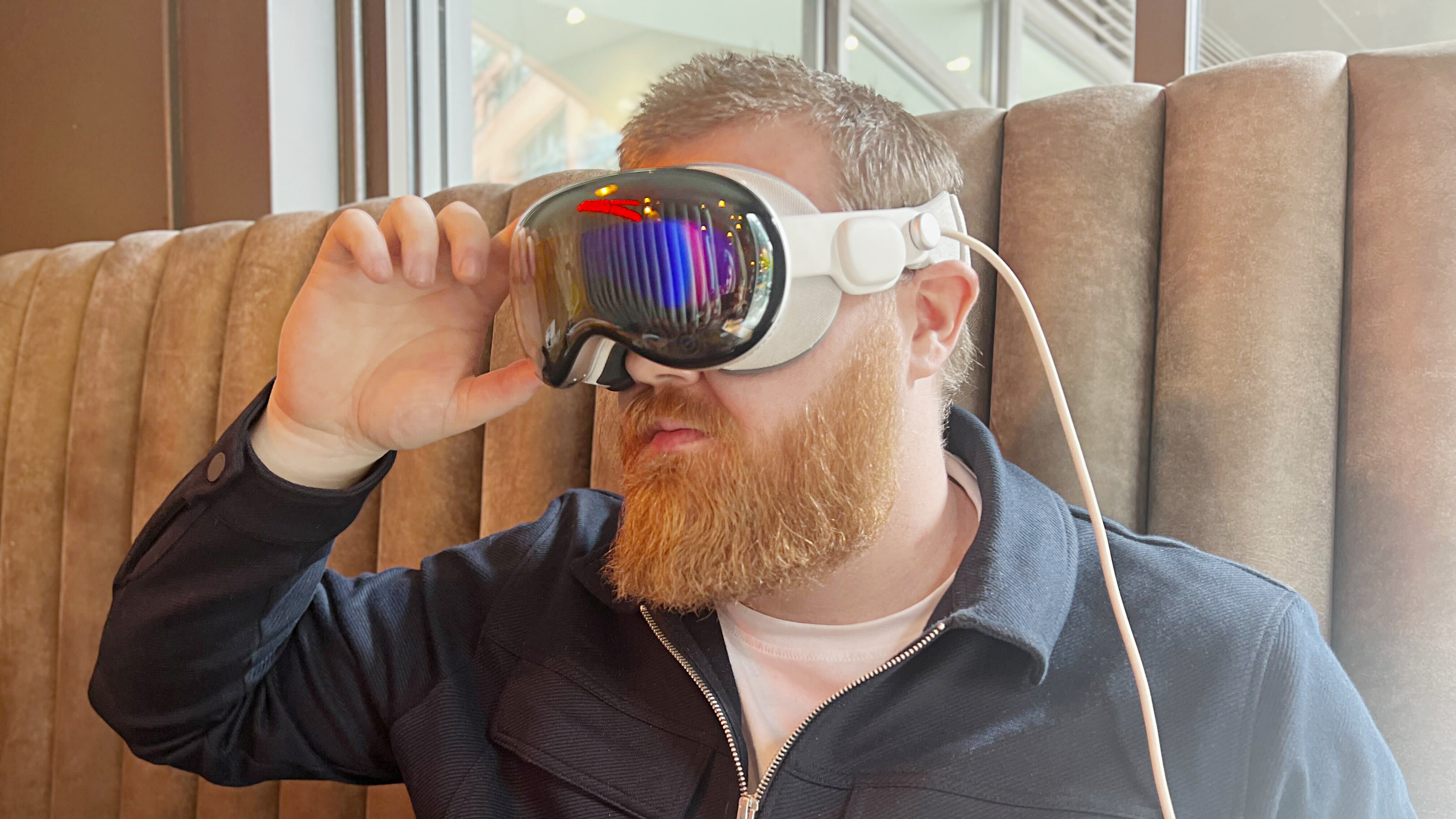 An individual wearing the Apple vision pro raising their hand to touch the goggles