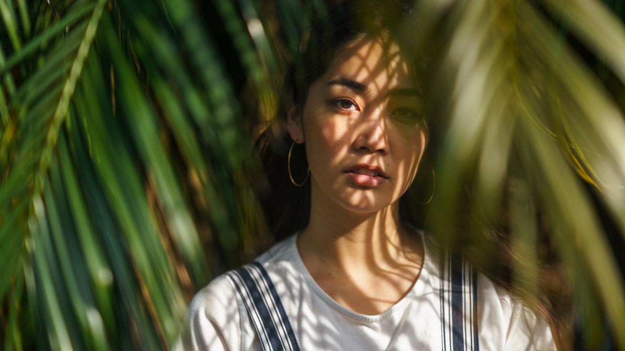 woman with sun on her face surrounded by trees