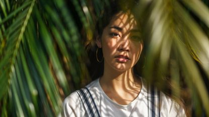 woman with sun on her face surrounded by trees