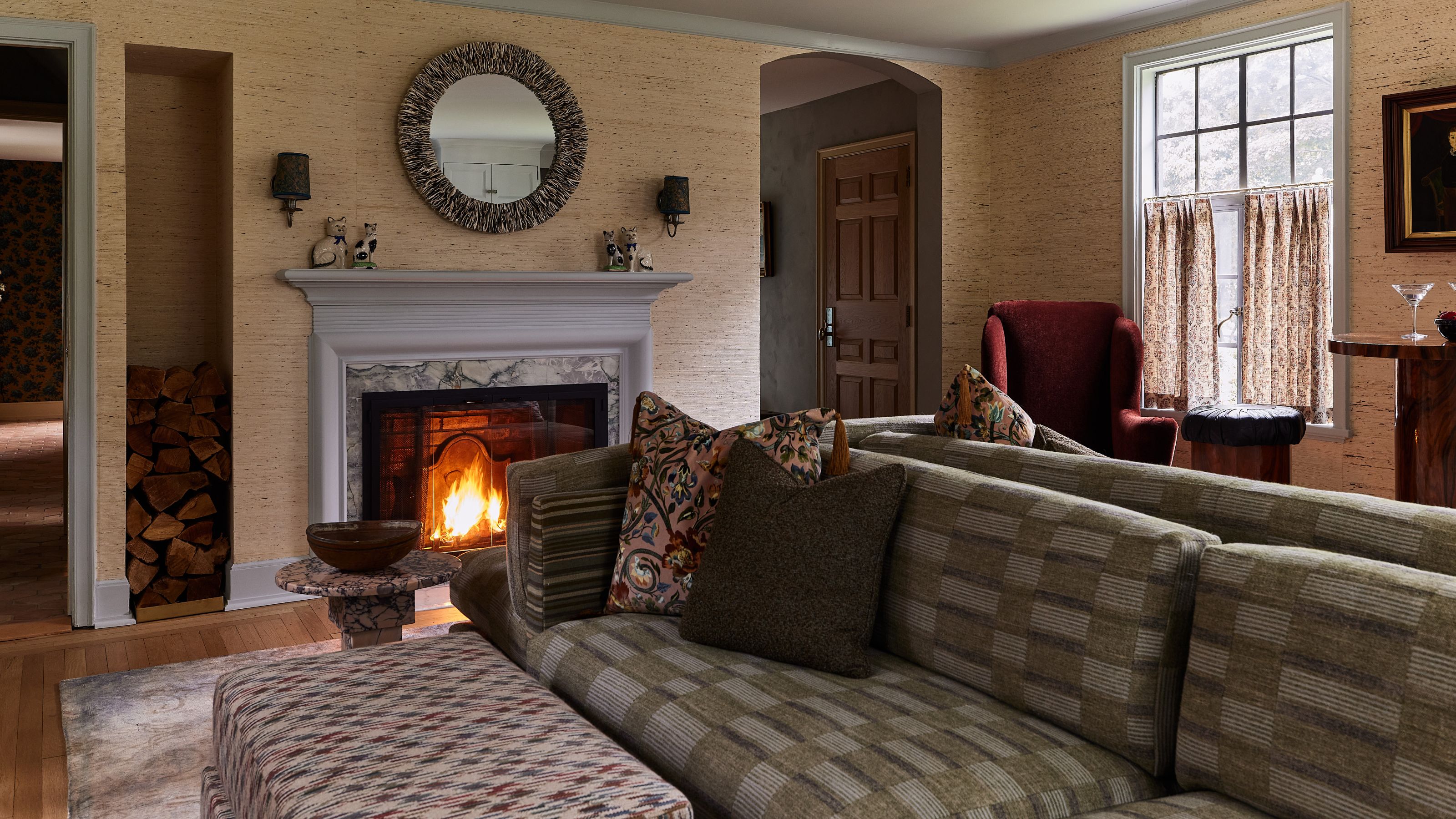 an open living room with grasscloth walls, painted blue gray trims and ceiling, marble fireplace, and a plaid three sided sofa