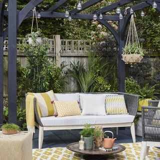 outdoor garden with hanging potted plant bulb lighting and sofa with cushions