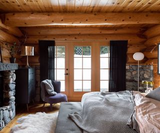 bedroom with wooden walls and stone fireplace and french doors