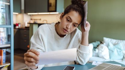 Woman sitting at a desk going over paperwork for her taxes and looking stressed