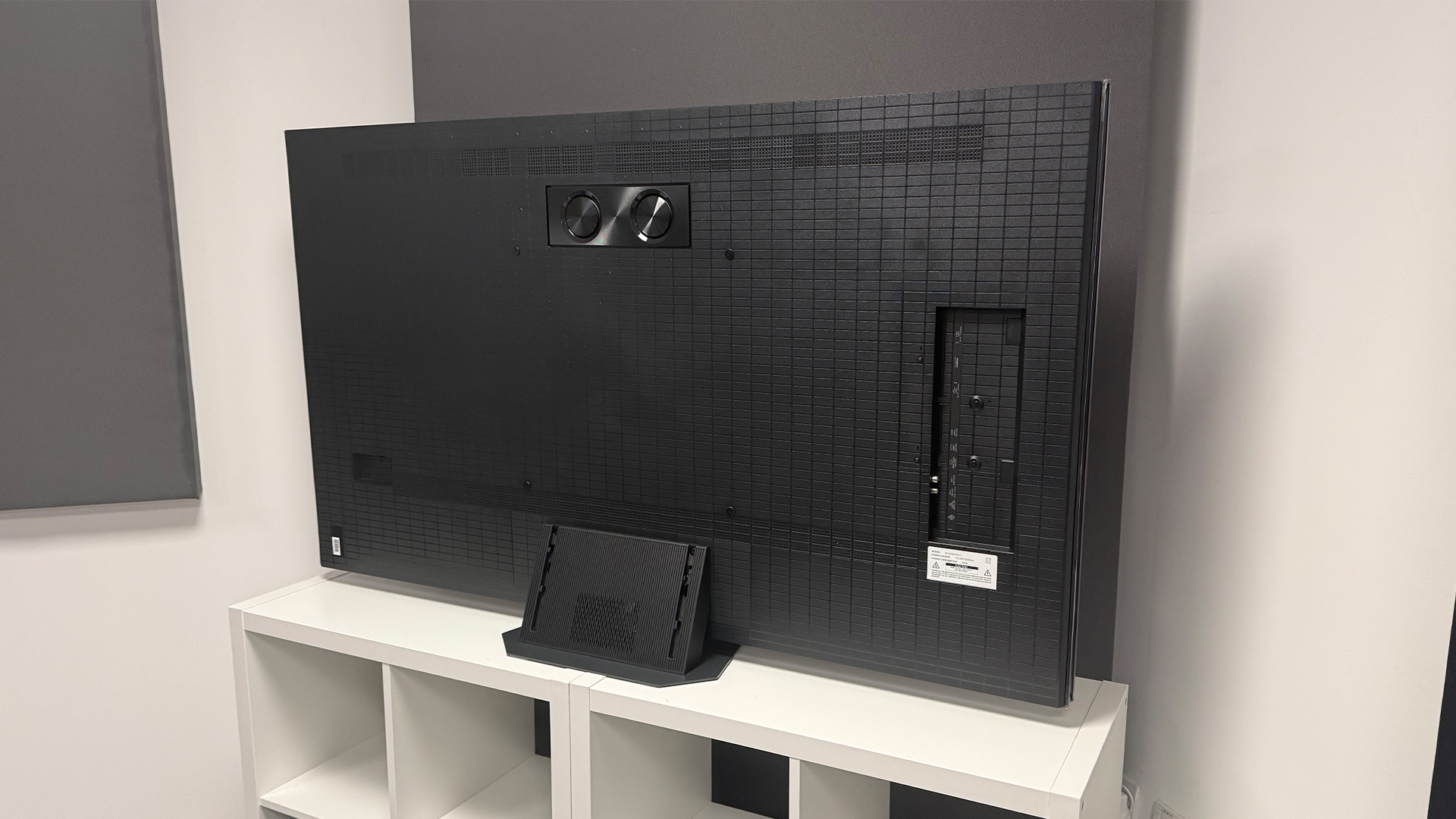 The 65-inch Hisense UR9 RGB Mini LED TV, photographed on a white, wooden unit. On the screen is a still from Netflix documentary, The Dinosaurs.