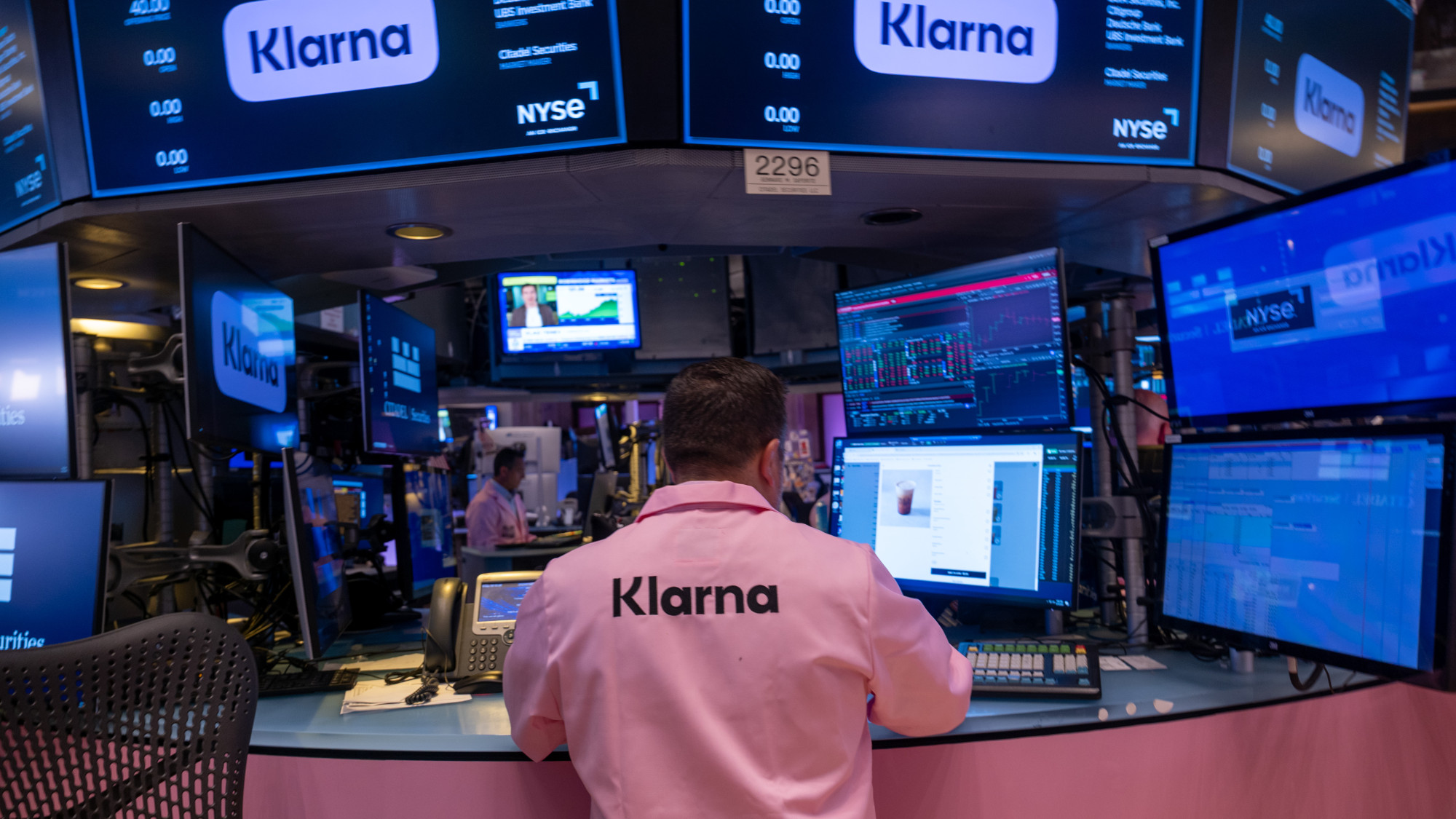 A man wearing a pink shirt with 'Klarna' written on the back