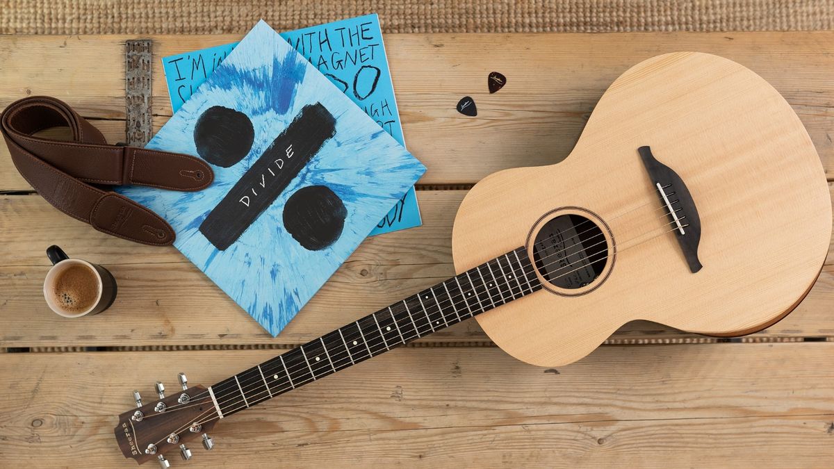 Ed Sheeran acoustic guitar on a wooden table with vinyl, picks, and guitar strap