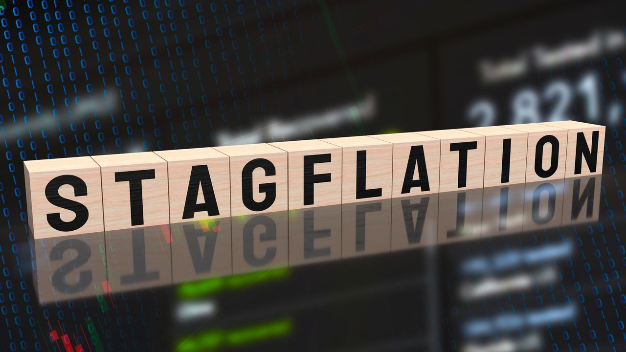 the word &quot;stagflation&quot; spelled out on wooden blocks with stock chart in the background