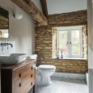 downstairs toilet with exposed beams, grey floor tiles, white basin with wooden cabinet