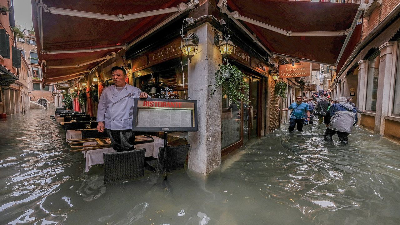 VENICE, ITALY - OCTOBER 29: A restaurant owner looks at the flood waters on October 29, 2018 in Venice, Italy. Due to the exceptional level of the "acqua alta" or "High Tide" that reached 156