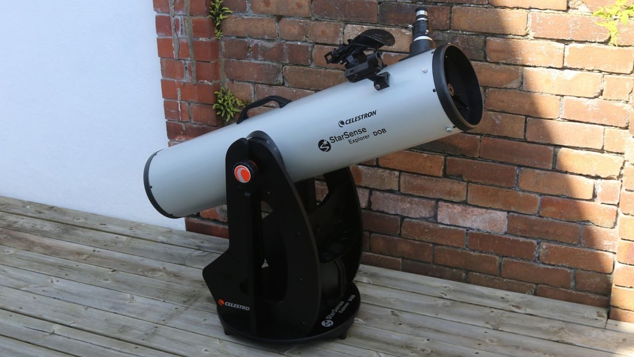 Celestron StarSense Explorer 8" Dobsonian telescope against a brick wall