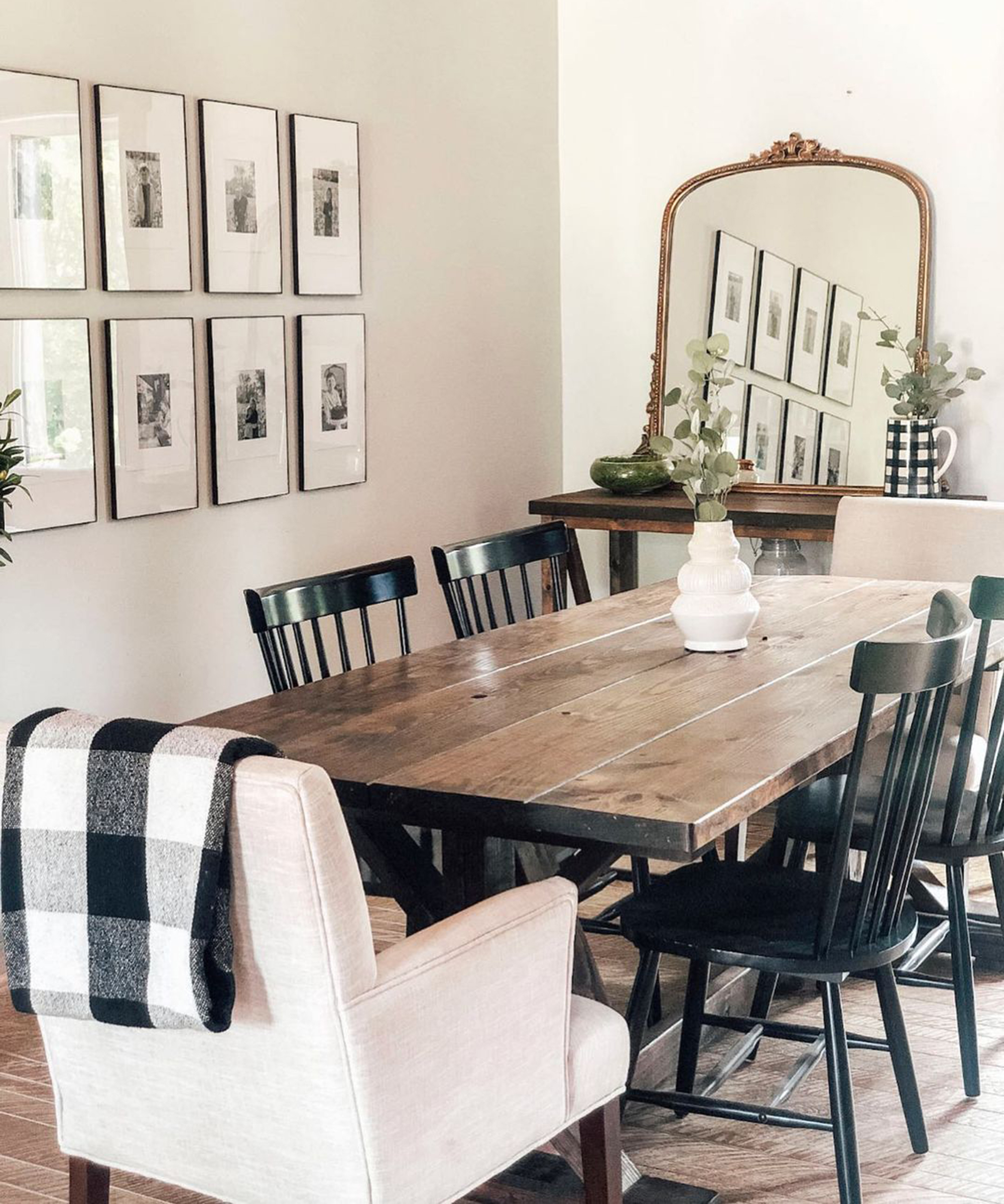 A dining room wall idea with monochrome photographs, black wooden chairs, plaid accessories and large mirror