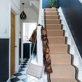 Brown stair runner with black and white flooring