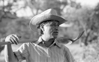 Cesar Chavez (1927 - 1993), founder of United Farm Workers (UFW), holds a shovel across his shoulders while working in the community garden at La Paz, California, 1975.