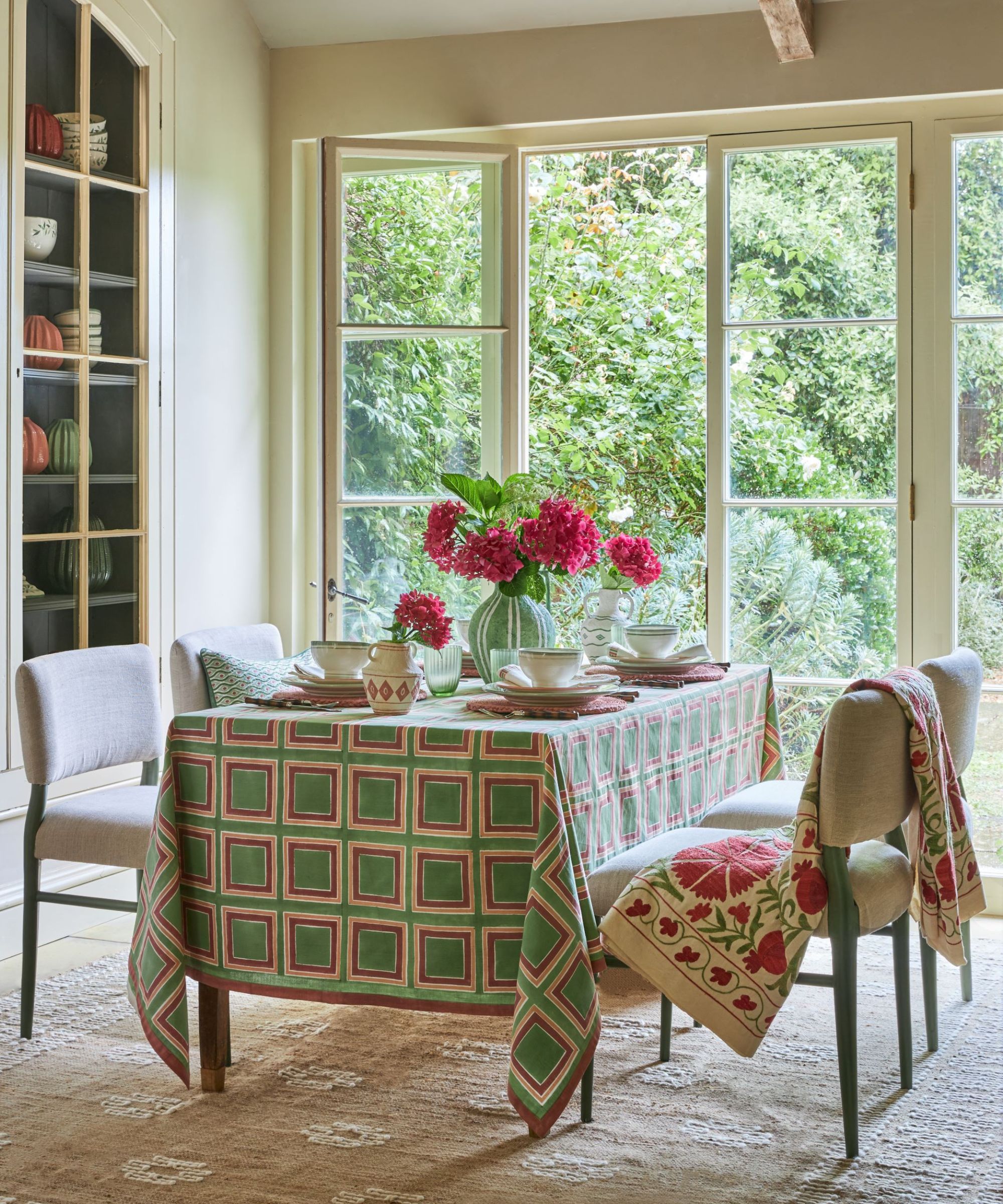 dining table with green geometric tablecloth and pink flower bouquet