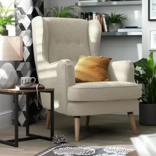 Wingback cream armchair in corner of a living room