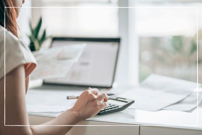 woman using calculator at desk at home