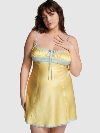 a model wears a yellow short slip dress with blue trim at the bust