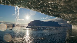 Setting midnight sun lights melting icebergs from Jakobshavn Isfjord along Disko Bay on summer evening.