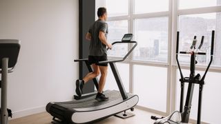 A man running on a treadmill by a window