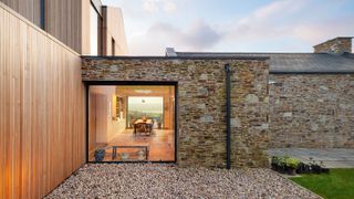 contemporary stone clad house with picture windows to create a through view
