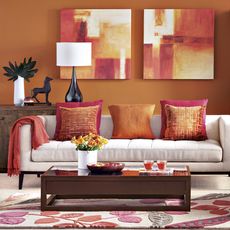 living room with orange walls and sofa with cushions