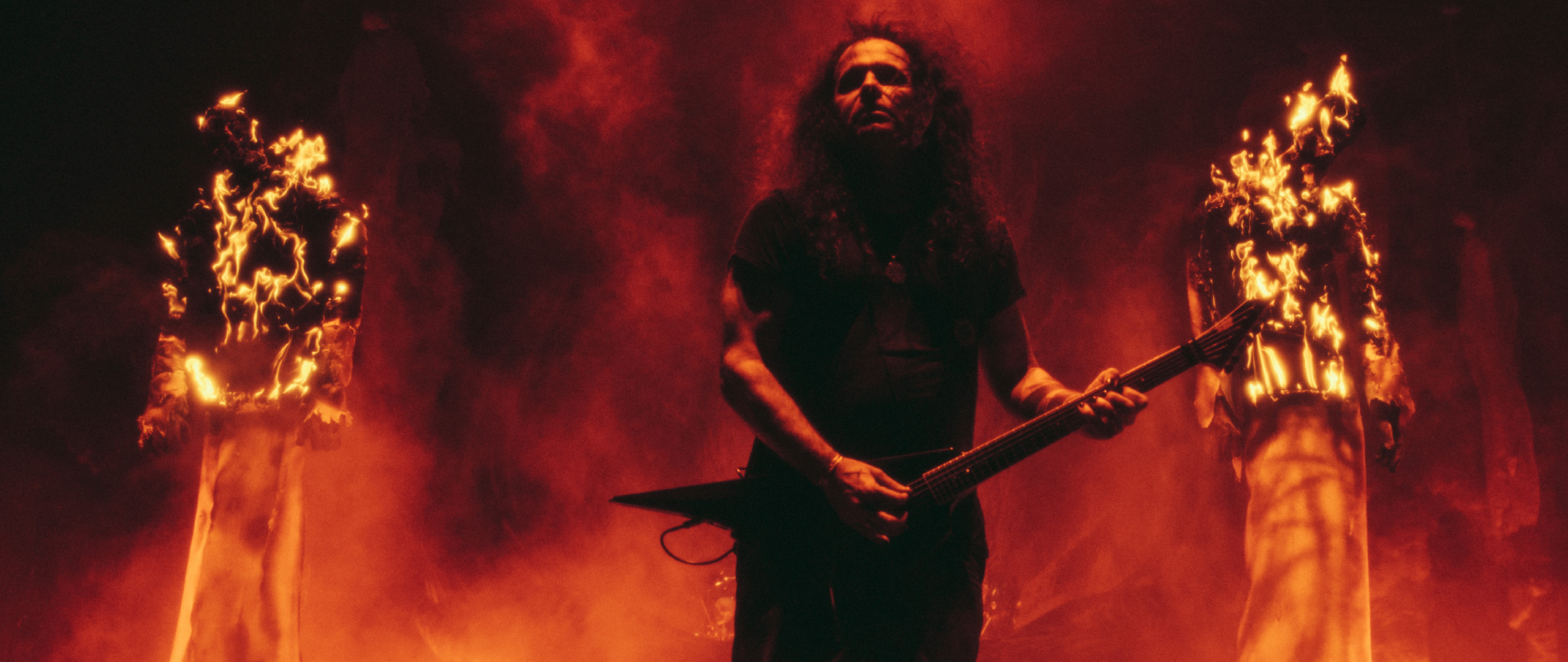 Mille Petrozza of Kreator onstage with two burning wicker men