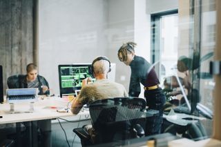 Software development team members discussing work in an office environment.