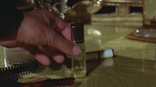 A perfume flamethrower being picked up from a desk in Moonraker.